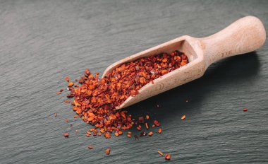 siyah arka plan üzerine bir kaşık kuru acı biber