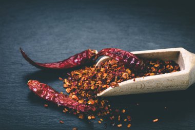 siyah taş zemin üzerine bir kaşık kuru acı biber