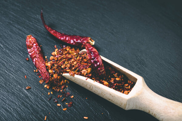 dry hot pepper in a scoop on black background