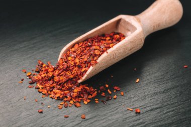 siyah taş zemin üzerine bir kaşık kuru acı biber