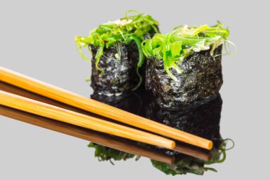 Suşi gunkan undaria ve siyah arka plan üzerine sopa ile