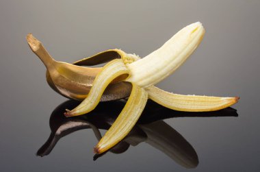 Altın kabuğu ile taze muz, yansıma ile siyah arka plan