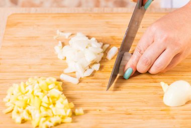 Cook ahşap tahta üzerinde bir bıçak ile soğan keser