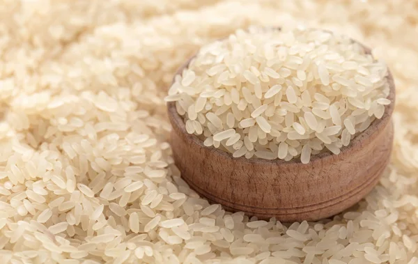 wooden bowl on a background of raw rice closeup