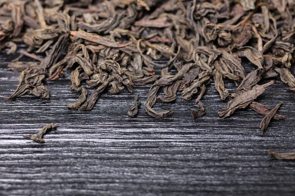 black dry large leaf tea on a wooden background