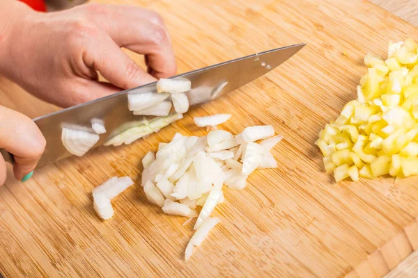 Cook ahşap tahta üzerinde bir bıçak ile soğan keser