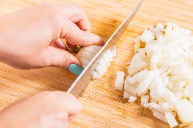 Cook ahşap tahta üzerinde bir bıçak ile soğan keser