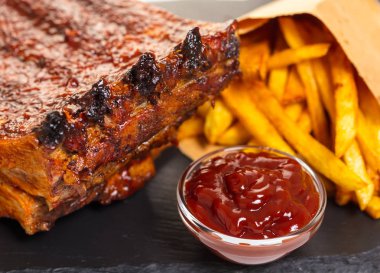 siyah bir arka planda patates ve sos ile ızgara kaburga