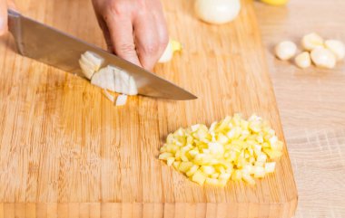 Cook ahşap tahta üzerinde bir bıçak ile soğan keser