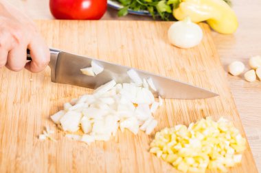 Cook ahşap tahta üzerinde bir bıçak ile soğan keser