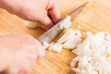 Cook ahşap tahta üzerinde bir bıçak ile soğan keser