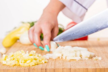 Cook ahşap tahta üzerinde bir bıçak ile soğan keser