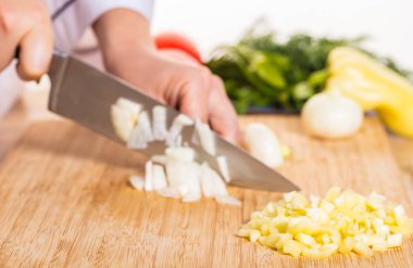 Cook ahşap tahta üzerinde bir bıçak ile soğan keser