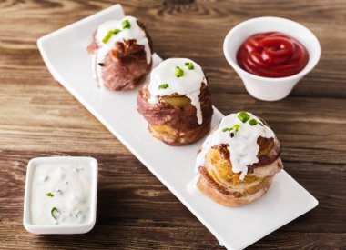 peynir ve soslar ile pişmiş domuz pastırması sarılmış patates