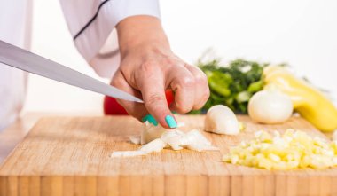 Cook ahşap tahta üzerinde bir bıçak ile soğan keser