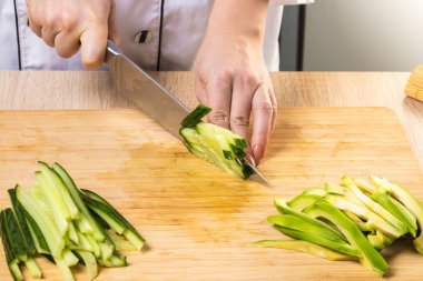 şef bir bıçakla salatalık keser, yakın eller