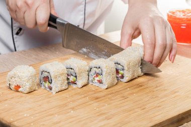 Japon mutfağı. Şef ruloları keser, eller yakın çekim