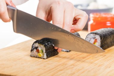 Japon mutfağı. Şef ruloları keser, eller yakın çekim