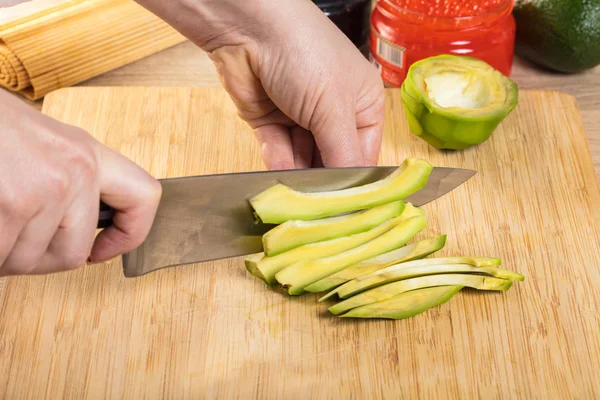 Chef Corta Abacate Com Uma Faca Mãos Close — Fotografia de Stock