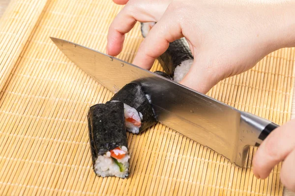 Japanese cuisine. Chef cuts rolls, hands close-up