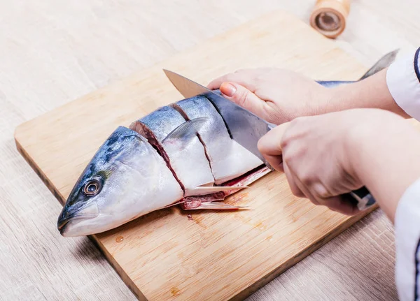 cook cuts raw tuna fish, hands closeup