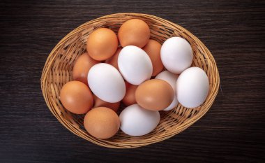 ahşap arka plan üzerinde bir hasır kapta tavuk yumurtası