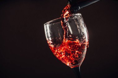Kahverengi arka plana kırmızı şarap dökülüyor.