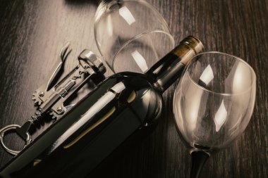 Ahşap arka planda bir şişe şarap ve tirbuşon.