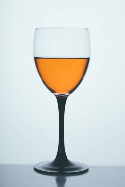 Aydınlık bir arkaplanda bir bardak beyaz şarap.