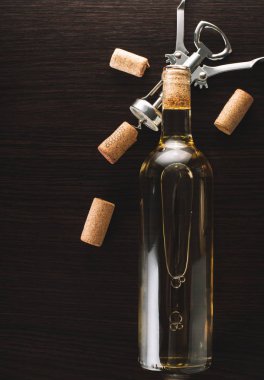 Ahşap arka planda bir şişe şarap ve tirbuşon.