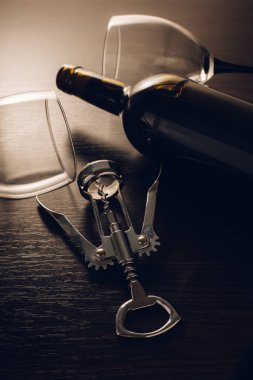 Ahşap arka planda bir şişe şarap ve tirbuşon.