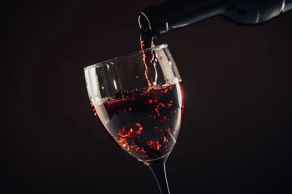 Kahverengi arka plana kırmızı şarap dökülüyor.