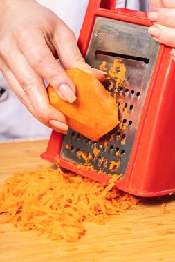 aşçı bir rende üzerinde havuç ovuşturuyor