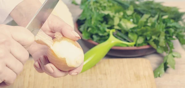 Cocinero limpia la piel de una cebolla — Foto de Stock