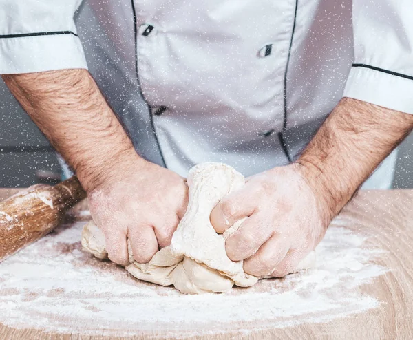 Male cook kneads dough on the table — Stock Photo, Image