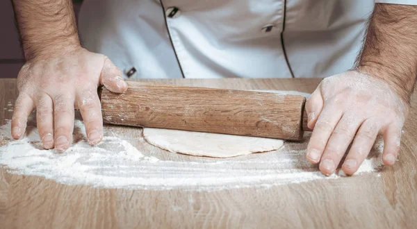 Male cook kneads dough on the table — Stock Photo, Image