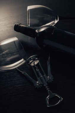 Ahşap arka planda bir şişe şarap ve tirbuşon.