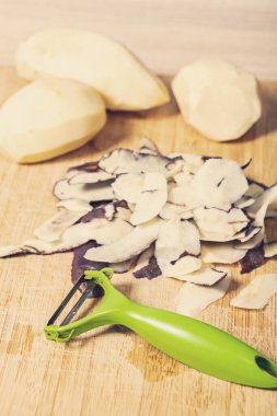 Tahta bir masada patates soymak, yemek hazırlığı.
