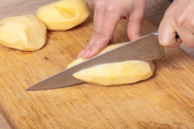 Aşçı patatesleri ahşap bir tahtada keser, yemek hazırlar.