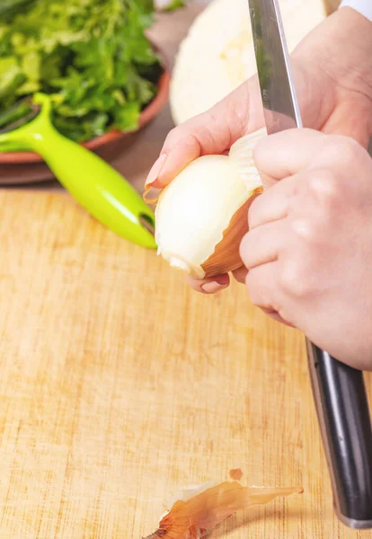 Aşçı bir soğanın derisini temizler, eller yakından.