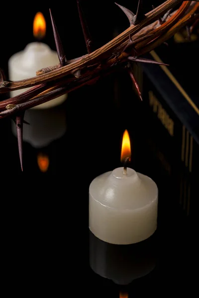 Close up of the crown of thorns and Bible in lights of candles — Stock Photo, Image