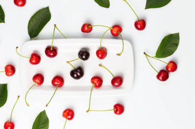 Olgun Kiraz çilek ve beyaz tabakta için izole kiraz yaprakları
