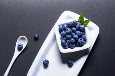 Üzerinde siyah ba taze yaban mersini meyve üzerinde beyaz seramik kase