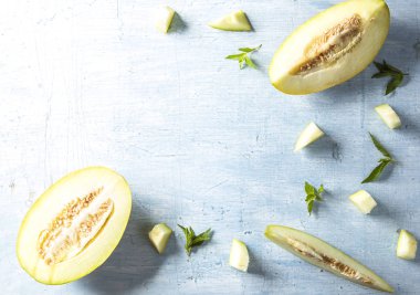 Mavi masa arka plan üzerine nane yaprakları ile dilimlenmiş kavun