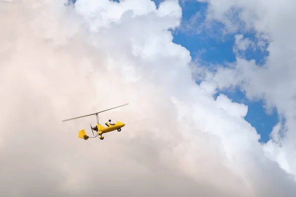 Small helicopter for two person flying on the cloudy sky