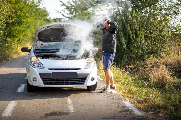 Un hombre ansioso cerca de un coche roto en la carretera — Foto de Stock