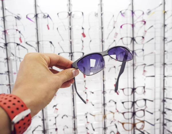 Személy kezét kiválasztásában a szemüveg napszemüveg optika üzlet — Stock Fotó