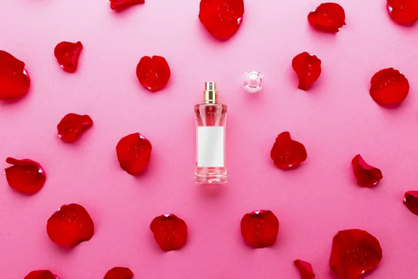 赤い背景の上のバラの花びら香水瓶 — ストック写真