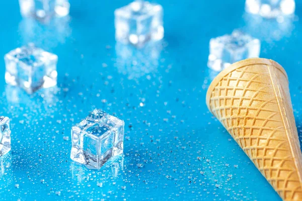 Prázdná zmrzlinový kužel a ledové kostky na modrém povrchu — Stock fotografie
