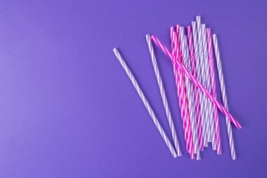 Mor arka planda çok renkli içme pipetleri